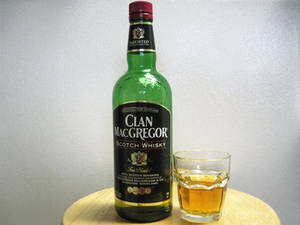 綠色威士忌酒瓶同木枱上嘅琥珀色液體玻璃杯。