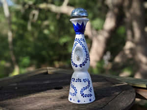 藍白圖案龍舌蘭酒瓶放在花園木桌上