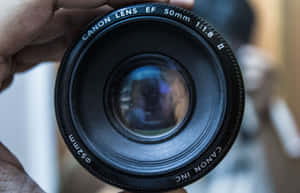 手持Canon 50mm f/1.8鏡頭，玻璃中可見反射。 — Steam Deck 壁紙