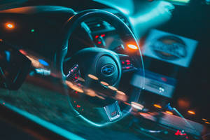 夜間被霓虹藍和橙色光照亮的汽車方向盤。