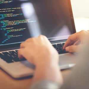 在溫暖照明的 workspace 中於筆記型電腦上輸入程式碼的人。