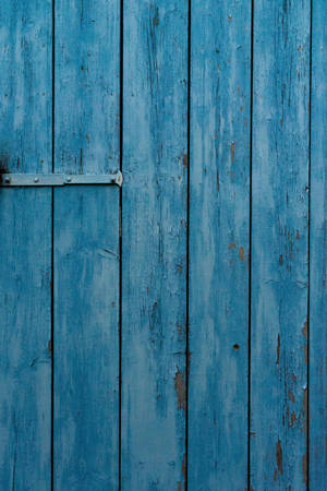  weathered blue wooden door with peeling paint and metal hinge。