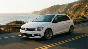 白色福士偉根Polo在海岸道路上行駛，海洋和懸崖