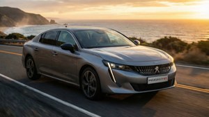 銀色Peugeot GT房車在日落時分行駛在海岸公路上，有海洋和懸崖