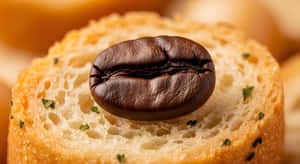一片灑有綠色香草的麵包上的深焙咖啡豆