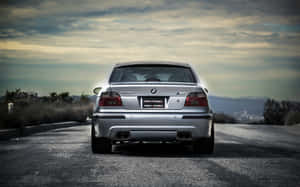 銀色BMW M5房車在黃昏時分的蜿蜒道路上，背景有山脈。 — 1280x800 壁紙