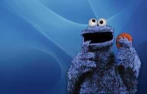 Cookie Monster 手持一塊朱古力曲奇，背景是藍色抽象圖案。 — 曲奇 壁紙