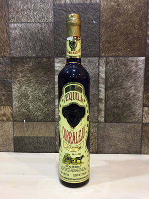 Corralejo龍舌蘭酒瓶置於木質表面上，背景為牛皮。