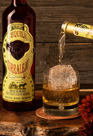 Corralejo 龍舌蘭酒被倒入一個放在木桌上的加冰玻璃杯中。