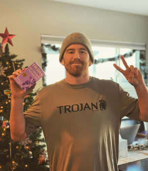 戴冷帽男子手持Trojan產品在聖誕樹旁做出和平手勢。