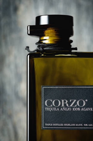 一款豪華龍舌蘭酒瓶，標有 Corzo Añejo，帶黑色瓶蓋和紋理灰色背景。