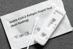 灰色表面上帶有棉花棒的陽性COVID-19快速抗原測試套裝。