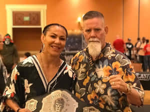 MMA 拳手 Cris Cyborg 在活動中與鬍鬚男手持冠軍腰帶。 — 冠軍 壁紙