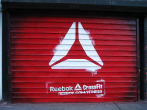 紅色金屬快門門，帶有白色Reebok CrossFit標誌和網站文字。
