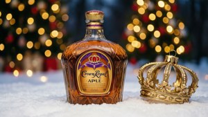 Crown Royal Apple 威士忌瓶和金色皇冠在雪地節日場景中。
