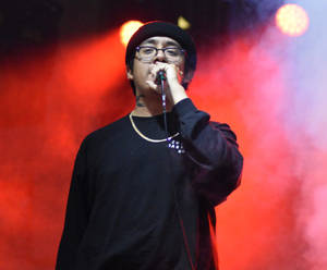饒舌歌手在紅燈和煙霧下於舞台上表演。