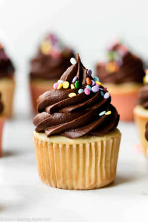朱古力紙杯蛋糕配彩色糖粒，放在大理石檯面上。