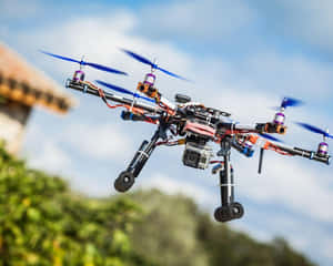 帶相機的自訂無人機在綠樹上方的天空中懸停 — 直升機 壁紙
