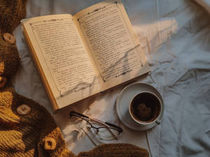 打開的書、咖啡杯和眼鏡在柔和的晨光中的床上
