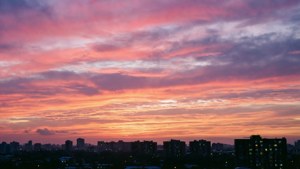 黃昏時分的城市天際線，色彩繽紛的雲朵和明亮的窗戶