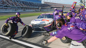 NASCAR維修站人員在日落時分的比賽中更換輪胎。