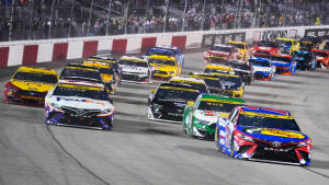 NASCAR賽車在夜間賽道上奔馳，伴隨著歡呼的粉絲。