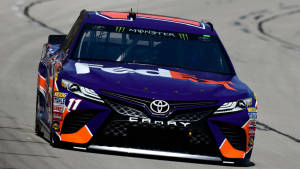 紫色和橙色的NASCAR賽車在賽道上飛馳。