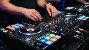 近距離拍攝DJ嘅手喺現場表演期間調整發光DJ控制器上嘅控制項。