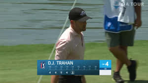 高爾夫球手 D.J. Trahan 在陽光明媚的高爾夫球場上行走，身後有水。