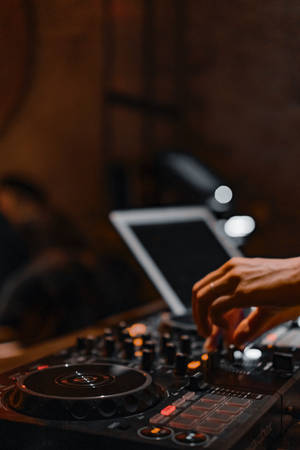 DJ的手在昏暗的房間中調整音樂控制器上的旋鈕。