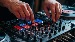 DJ雙手調整發光音樂混音器和唱盤上的控制。