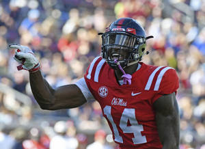 穿著紅色 Ole Miss 14號球衣的美式足球員在比賽中舉起拳頭慶祝。