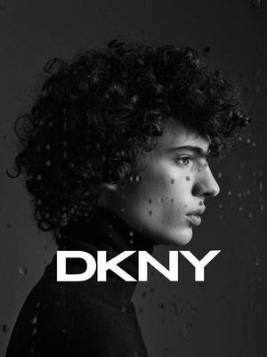 在DKNY廣告中，有曲髮的人物透過玻璃上的雨滴側視。