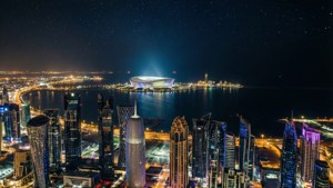 夜晚的未來城市天際線，燈火通明的塔樓和星空下的海濱體育場。