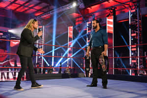 兩名男性摔角手在色彩繽紛的舞台燈光下，在摔角擂台上對峙。 — 摔角 GIF 壁紙