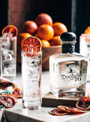 在大理石表面上，一瓶Don Julio 70龍舌蘭酒配上一杯冰塊和乾血橙裝飾。