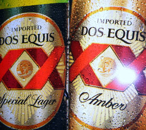 兩罐冰冷的Dos Equis啤酒罐，標籤上有水珠。