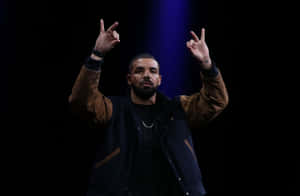 Drake 在舞台上舉起雙手做手勢表演。
