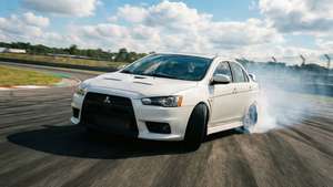 白色三菱Lancer Evolution在賽道飄移，帶有煙霧