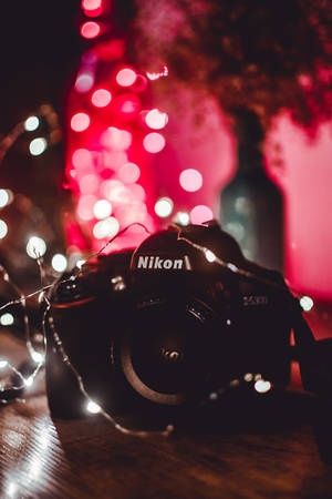夜晚，一張木桌上，一部Nikon相機被發光的仙女燈環繞。
