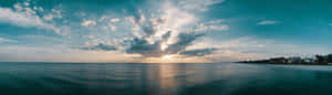 海洋上的日落，有雲和遠處的海灘房屋