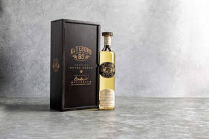 El Tesoro 88 Tequila Extra Añejo酒瓶和木盒放在灰色混凝土表面上。