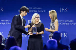 年輕男子在JFK Courage Award頒獎典禮上向女性頒發玻璃獎項。 — 政治 壁紙