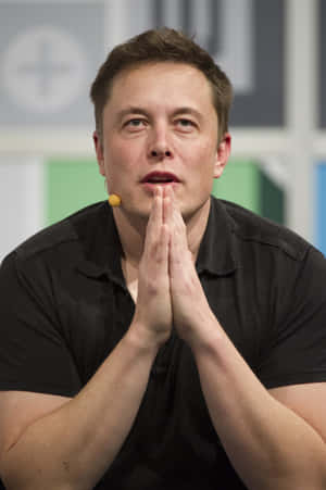 Elon Musk 喺活動中雙手合攏喺嘴邊講嘢。 — POCO Pad 壁紙
