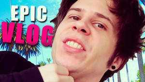 年輕男子微笑，身後有棕櫚樹和「EPIC VLOG」文字。