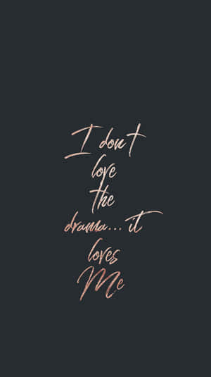 深灰色背景上以玫瑰金草書文字寫著「I don't love the drama... it loves Me」。