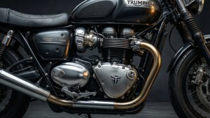 黑色Triumph電單車引擎，帶有鍍鉻和金色排氣管，在影樓燈光下