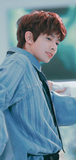 紅髮年輕男子穿著藍色條紋襯衫微笑。