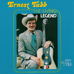 Ernest Tubb 在藍色背景上戴著牛仔帽拿著結他微笑
