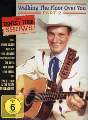 Ernest Tubb 身穿白色牛仔套裝，手持帶有名稱帶的木結他。